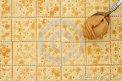 Saltine crackers background with spoon full of peanut butter Stock Photo