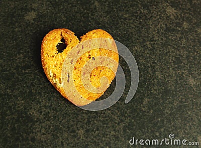 Salty croutons with bread on a dark background, in the shape of a heart, in a close-up Stock Photo