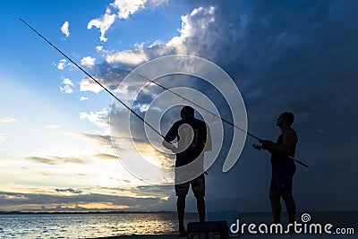 Silhouette of fishermen with their poles at sunset Editorial Stock Photo