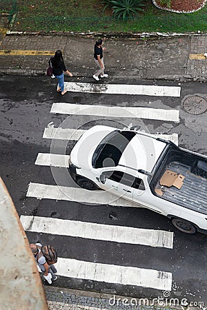 Salvador, Bahia, Brazil - August 11, 2023: View from above of a car and pedestrians crossing the lane on one of the streets next Editorial Stock Photo