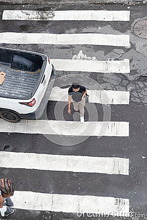 Salvador, Bahia, Brazil - August 11, 2023: View from above of a car and pedestrians crossing the lane on one of the streets next Editorial Stock Photo