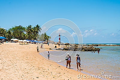 People at the beach and a view of Itapua Lighthouse Farol de Itapua, popular landmark Editorial Stock Photo