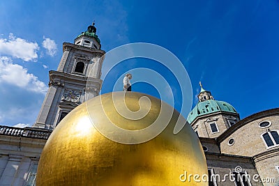 Salzburg Kapitelplatz with huge gold ball Goldkugel with a man and a church Stock Photo