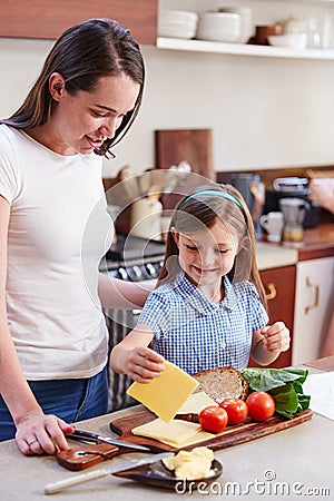 Same Sex Female Couple With Daughter Preparing School Lunchbox At Home Together Stock Photo