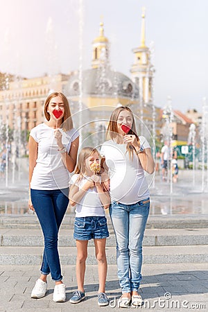 Samesex lesbian family with child on a walk in the park near the fountains. Lesbians mothers with adopted child, happy Stock Photo