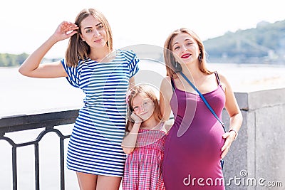 Samesex lesbian family with child on a walk in the park near the river. Lesbians mothers with adopted child, happy Stock Photo