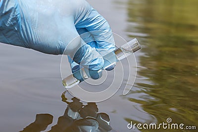 Sample water from the river for analysis. Hand in glove holding Stock Photo