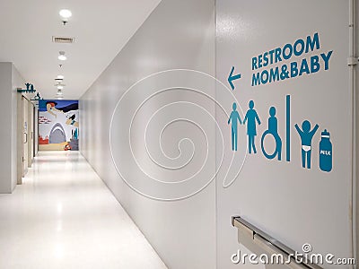 Blue disabled wheelchair and a family restroom sign on white modern wall in clean corridor inside of shopping mall Editorial Stock Photo