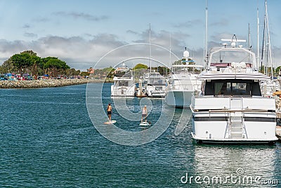 San Diego, Luxury Yachts in Embarcadero Marina Park and Attractive Women on Stand Up Paddle Boards Editorial Stock Photo