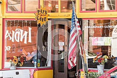A United States flag in front of the glass of a coffee shop in San Francisco, California, Spain. Editorial Stock Photo