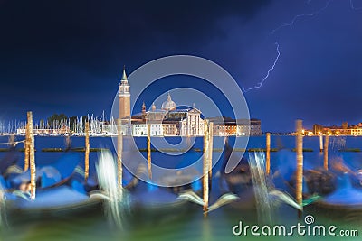 San Giorgio Maggiore church and gondolas in Venice, Italy during blue hour with dramatic sky and lighting. Focus on the church. Stock Photo