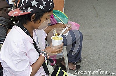 Wheelchair female Beggar holding a cup of gruel Editorial Stock Photo