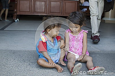 Homeless beggar`s children boy and girl, seated, take care of each other at church yard Editorial Stock Photo