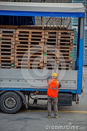 Truck driver secures the loading of bottles of mineral water by binding it with ropes before starting the transport Editorial Stock Photo