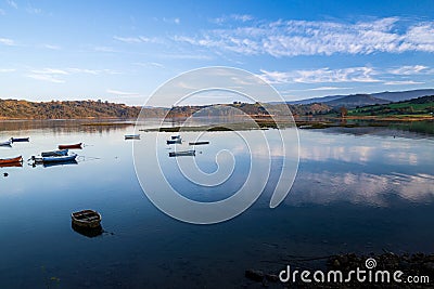 Reflections of clouds with fishing boats docked. San Vicente de la Barquera, Cantabria, Spain. Stock Photo