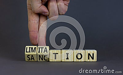 Sanction and limitation symbol. Businessman turns cubes, changes the word limitation to sanction. Beautiful grey table, grey Stock Photo