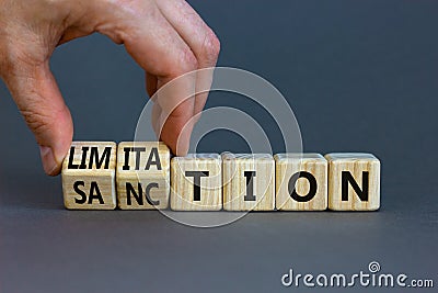 Sanction and limitation symbol. Businessman turns cubes, changes the word limitation to sanction. Beautiful grey table, grey Stock Photo