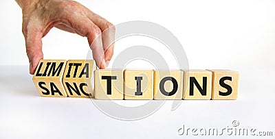 Sanctions or limitations symbol. Businessman turns cubes, changes the word sanctions to limitations. Beautiful white table, white Stock Photo