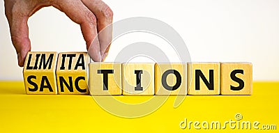 Sanctions or limitations symbol. Businessman turns cubes, changes the word sanctions to limitations. Beautiful yellow table, white Stock Photo