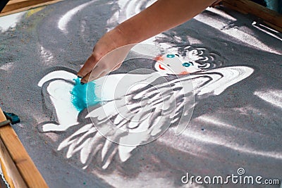 Sand animation, drawing sand closeup, girl drawing an angel on the sand Editorial Stock Photo