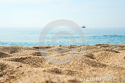 Sand on the beach close up with blurred sea, ship and waves on a background. Stock Photo