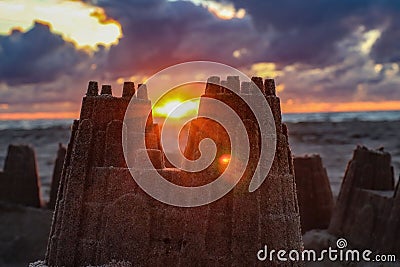 sand castle with sun in background on the beach at sunrise Stock Photo