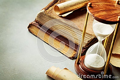 Sand running through the hourglass and old vintage books. Time keeper concept. Stock Photo