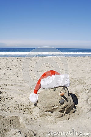 A Sand Snow Man on the Beach with a Santa Hat for Christmas Stock Photo