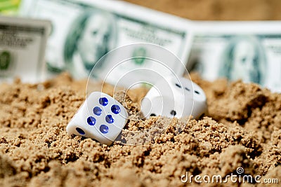 In the sand two game cubes in the foreground, the background is blurred out of focus there money Stock Photo