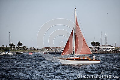 Sandbanks, Dorset, England - June 02 2018: A sail boat sailing through Poole Harbour, on a clear sunny summer day, with the luxury Editorial Stock Photo