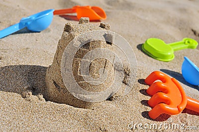 Sandcastle and toy shovels on the sand of a beach Stock Photo