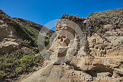 Sandstone cliff with Pirate Skull markings on beach Stock Photo
