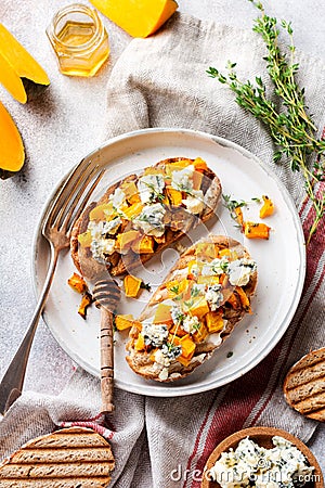 Sandwich with baked pumpkin and dorblu cheese with blue mold, honey and thyme on a concrete old light background. Top view Stock Photo