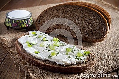 Sandwich with cream, dill and chives and dark rye bread and salt in saltshaker on burlap. Close-up Stock Photo