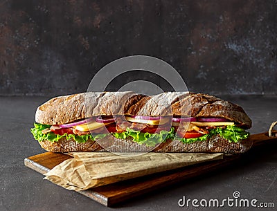 A sandwich of dark bread with salad, bacon, tomatoes, cheese and onions. Breakfast. Fast food Stock Photo