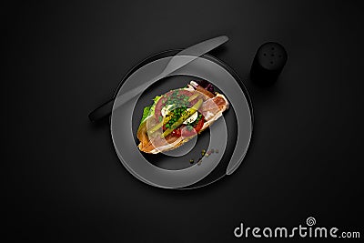 Canape with prosciutto on a black plate Stock Photo