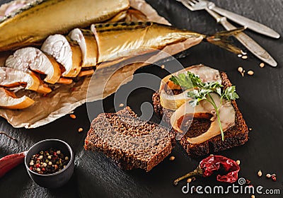 Sandwich with smoked mackerel fish with spices on dark stone background. Smoked fish, mediterranean food, herring fish, seafood, Stock Photo