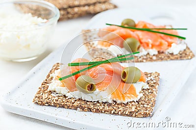 Sandwich with smoked salmon and cream cheese on thin multi seed crispbread, garnished with green onion and olives, horizontal Stock Photo
