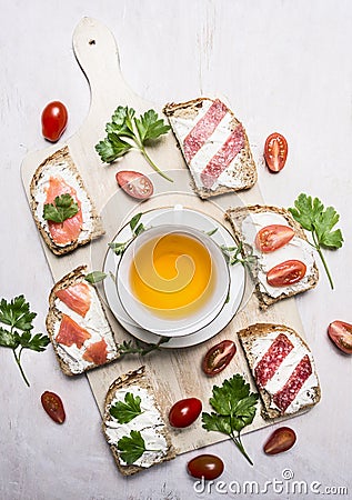 Sandwiches with salmon and salami, parsley tea and lunch on wooden rustic background top view Stock Photo