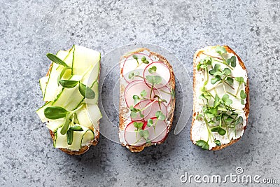 Sandwiches with sundries tomatoes, fresh radish, microgreens, cream cheese on grey background. Stock Photo