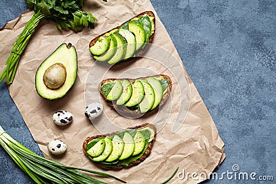 Sandwiches toast with avocado, guacamole and spinach on parchment on a concrete background. Healthy breakfast or lunch Stock Photo