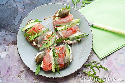 Sandwiches with trout, capers and arugula on blue plate Stock Photo