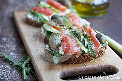 Sandwiches with trout, capers and arugula on wooden desk Stock Photo