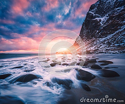 Sandy beach with stones in blurred water, colorful sky Stock Photo