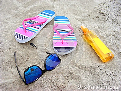 Sandy beach with sunglasses, flip-flops and suncare milk Stock Photo