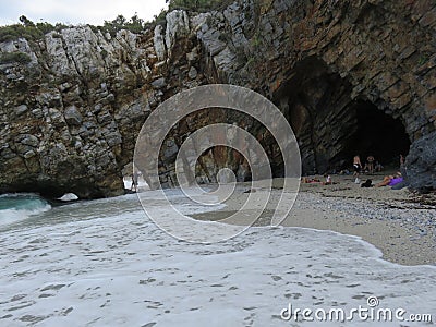 Sandy seashore with narrow passage through the rocky coastline Stock Photo