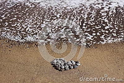 On the sandy shore lies a heart of sea stones. The concept of openness, friendship and religion Stock Photo