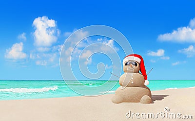 Sandy snowman in Christmas Santa hat and sunglasses at beach Stock Photo