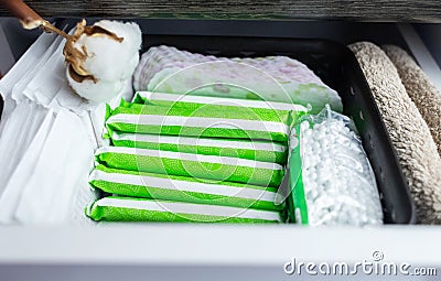 Sanitary napkin, tampon and cotton plant flower. Women hands pull out drawer containing hygiene products to help with menstruation Stock Photo