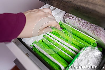 Sanitary napkin, tampon and cotton plant flower. Women hands pull out drawer containing hygiene products to help with menstruation Stock Photo